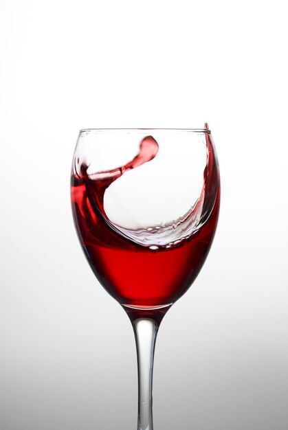 写真 白い背景のクリスタルグラスに赤ワインのスプラッシュ