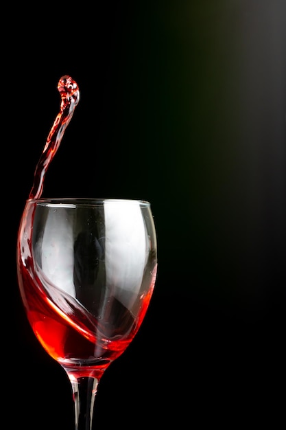 Splash of red wine in a glass on a black background