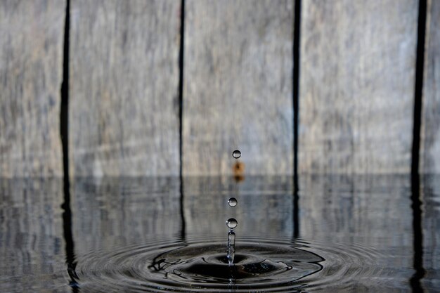 木製の背景に落ちた雨滴からの水のしぶきと波紋。