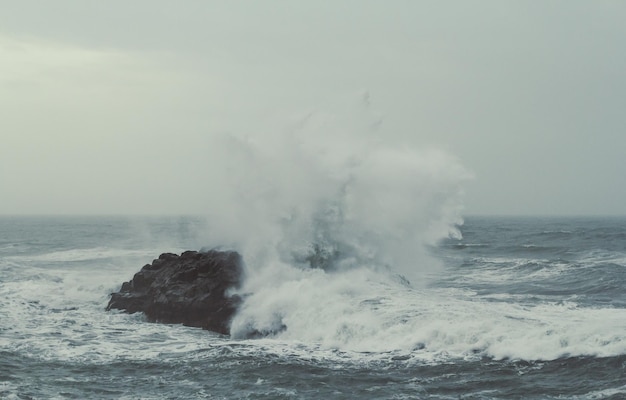 Splash sea water over rock on storm landscape photo