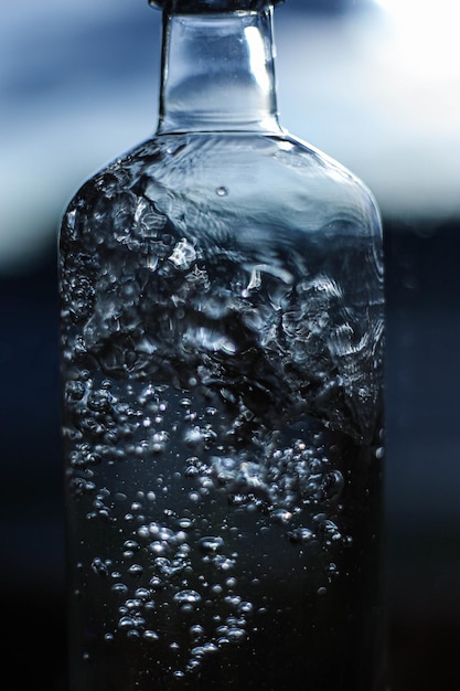 暗い光の背景にボトルのクローズアップの水のしぶき水の詳細水の構造