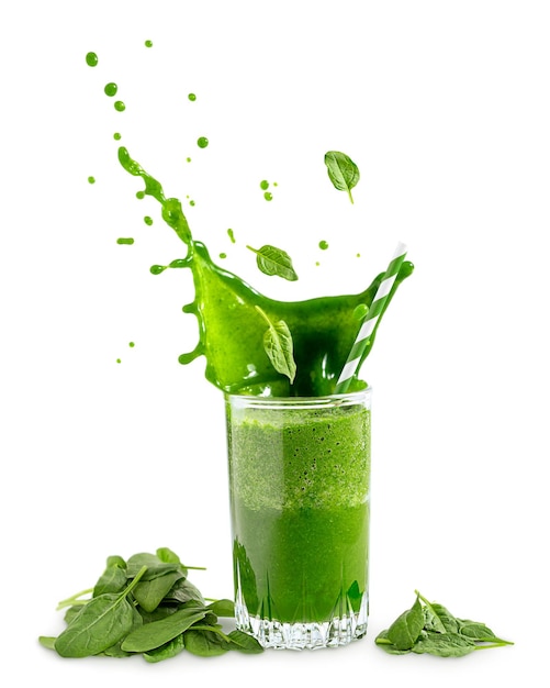 白い背景の上のグラスに緑の有機ほうれん草のスムージーまたはジュースの滴をはねかける