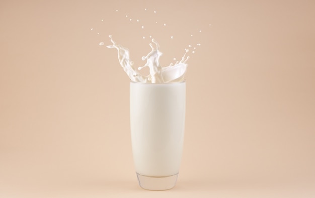 Splashes of milk in a glass isolated on beige background