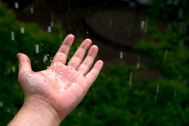 Splashing droplets from the rain on the man's hand in nature