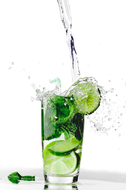 Photo splashing mojito cocktail with lime and mint isolated on white background