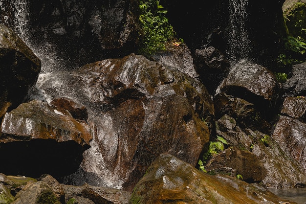 튀는 물. 전경에 있는 젖은 바위에 초점을 맞춘 사진, 폭포 방울