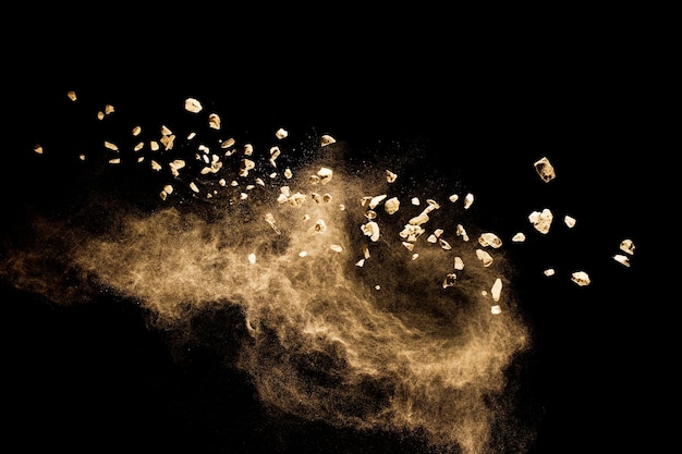 Split debris of stone exploding with brown powder against black background