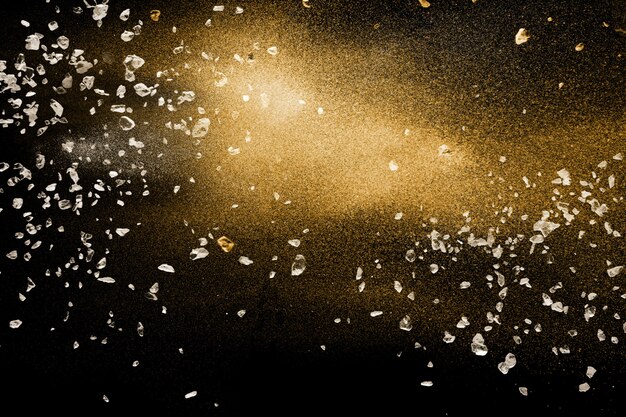 Photo split debris of stone exploding with golden dry river sand against black background.