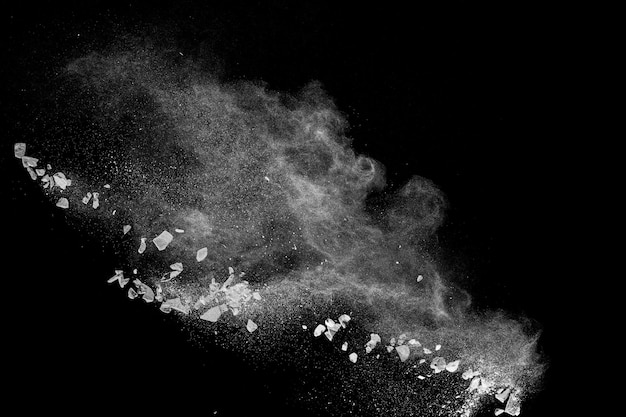 Detriti spaccati di pietra che esplodono con polvere bianca su sfondo nero