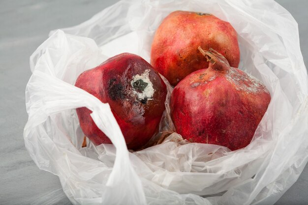 Spoiled pomegranates with mold in disposable plastic bag