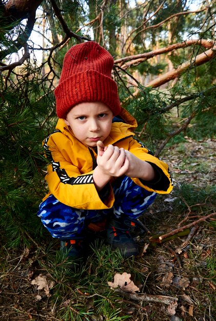 Spoils the boy in a jacket and hat in the forest