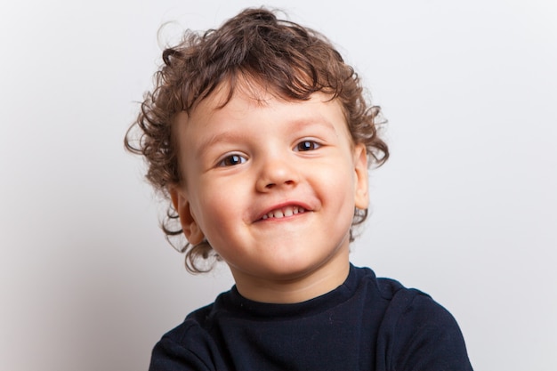 Vizia un ragazzo carino e riccio, un bambino. sorriso divertente