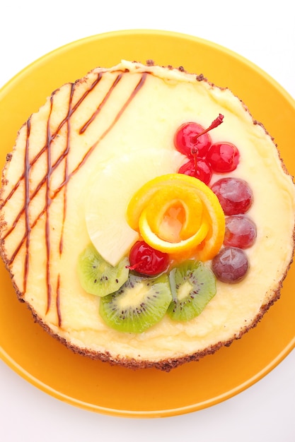 Sponge cake decorated with icing and fruit on a white background