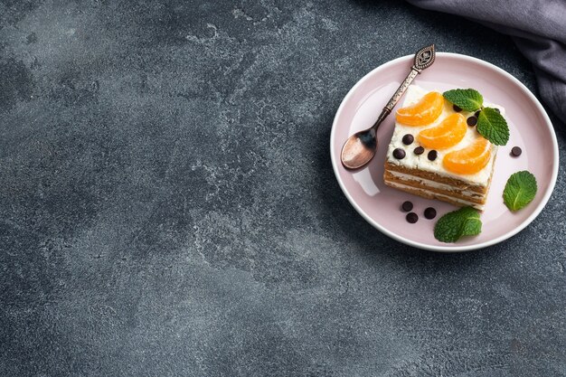 Sponge cake layers with buttercream, decorated with slices of tangerine chocolate and mint. Delicious sweet dessert for tea. top view, copy space.