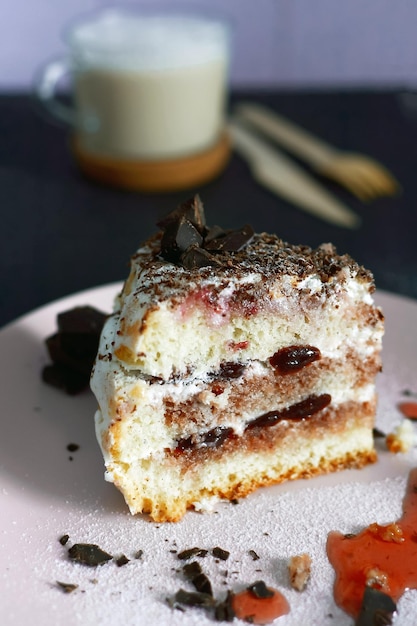 Pan di spagna con frutti di bosco primo piano su uno sfondo di caffè cappuccino e posate in legno