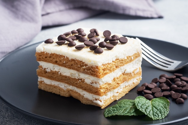 Pan di spagna con crema di burro e pezzi di cioccolato alla menta su un piatto nero. dessert per festeggiare eventi o feste di compleanno.