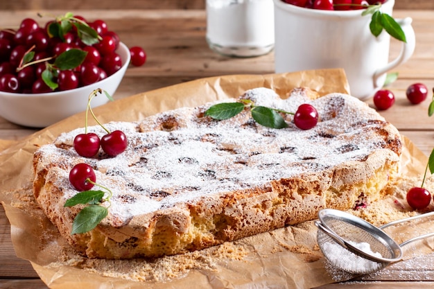 Sponge cake with cherries on a board on the table Homemade pie