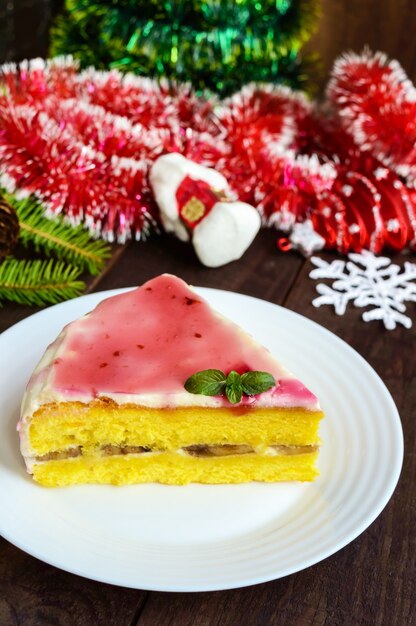바나나, 우유 크림, 크랜베리 시럽을 얹은 스폰지 케이크. 크리스마스 휴일 디저트.