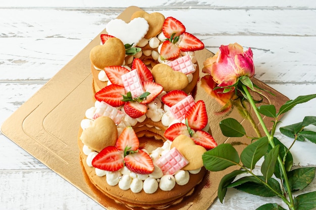 Sponge cake with strawberries pink chocolate bars vanilla cream
and heart chape cookies in shape of number 8 with pink rose a gift
for special one for international women day sweet present