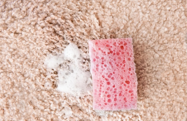 Foto spugna e detergente su un tappeto morbido da vicino