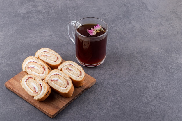 Sponge swiss roll cake with glass pitcher of milk .