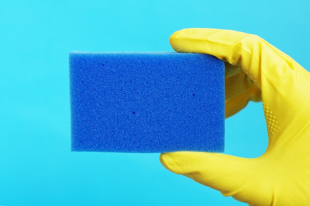 Photo sponge for washing dishes in hand in a yellow rubber glove