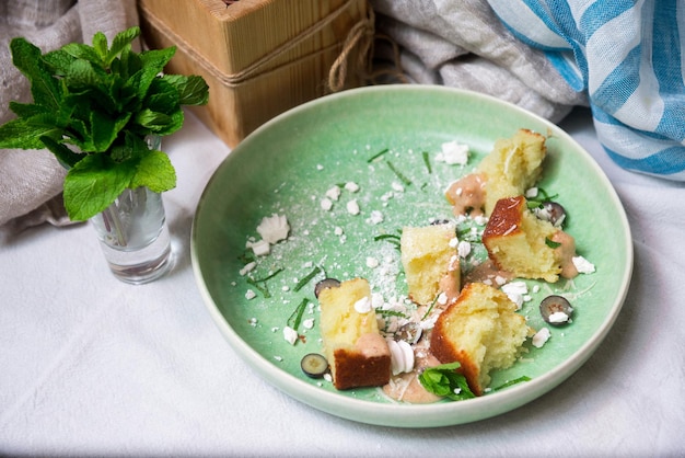 테이블 위의 녹색 접시에 설탕 가루와 얇게 썬 민트 잎을 넣은 스펀지 비스킷 조각