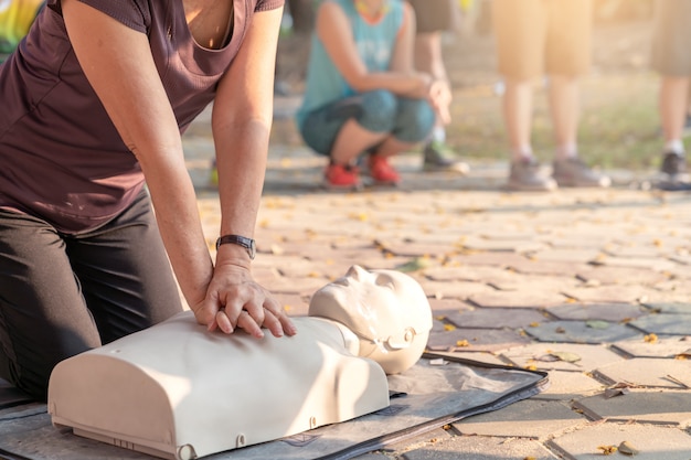 Foto spontaan van rijpe aziatische vrouwelijke of oudere agentvrouw opleiding op cpr die klasse in openluchtpark aantonen en handen overhandigt cpr-pop op borst. ehbo-training voor mensen met een hartaanval of levensredder.