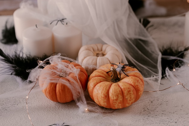 Spooky Halloween decoration with different pumpkins, light, spiders. 