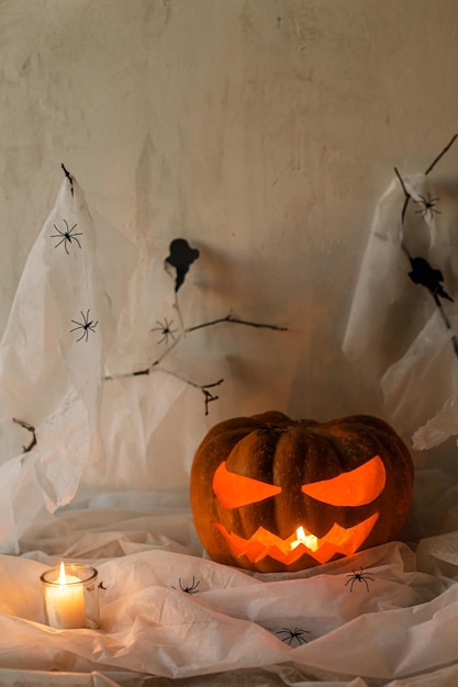 Spooky Jack o lantern carved pumpkin spider web ghost bats and glowing candles in evening Happy Halloween Scary atmospheric halloween party decorations space for text Trick or treat
