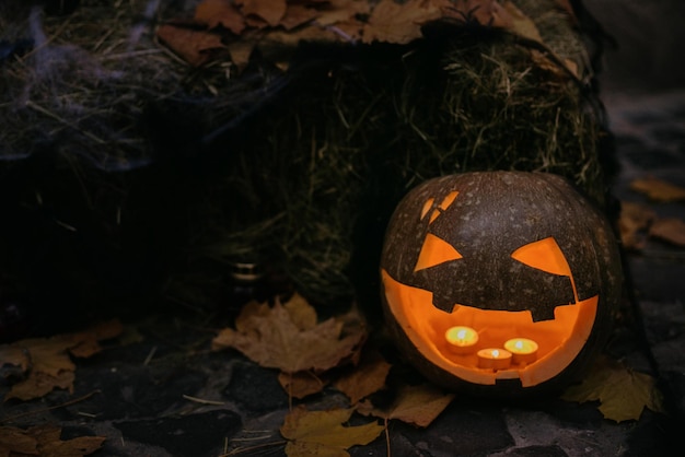 Spooky Jacko'lantern met gloeiende gezichten en spinneweb in het donker Pompoen met eng gesneden gezicht op hooi met kaarslicht modern feestelijk halloween straatdecor Happy Halloween