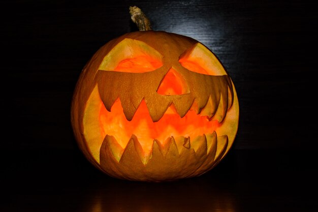 Spooky luminous halloween pumpkin on black background