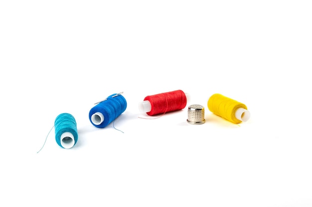 Spool of blue red and yellow threads with a needle on a white isolated background