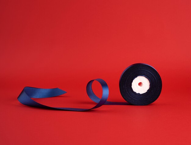 Spool of twisted dark blue silk shiny ribbon on red