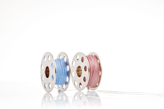 Spools of blue and pink thread on a white background