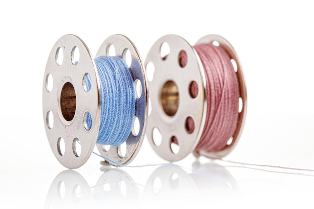 Spools of blue and pink thread on a white background