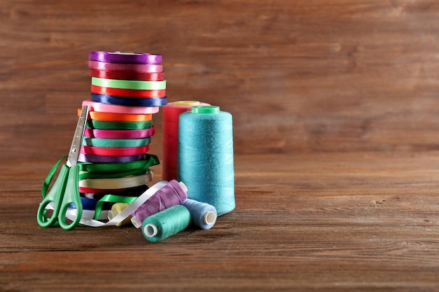 Spools of color ribbon with scissors thread on wooden background