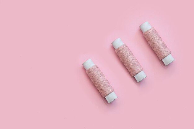 Spools of pink thread on a pink background sewing concept