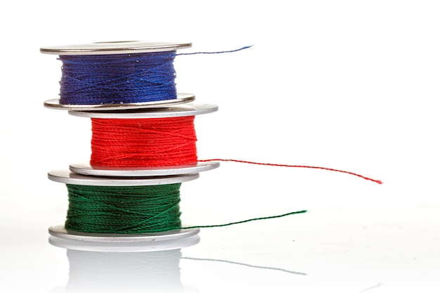 Spools of thread in blue red green colors on a white background