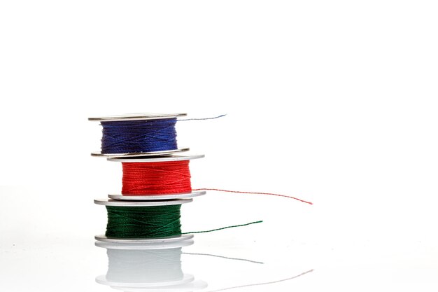 Spools of thread in blue red green colors on a white background