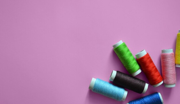 Spools of thread on a pink background a banner for an atelier tailoring sewing threads a photo for a sewing workshop a place for text