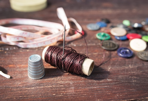 Spools of threads and buttons on old wooden table