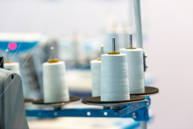 Spools of white threads on sewing machine, closeup