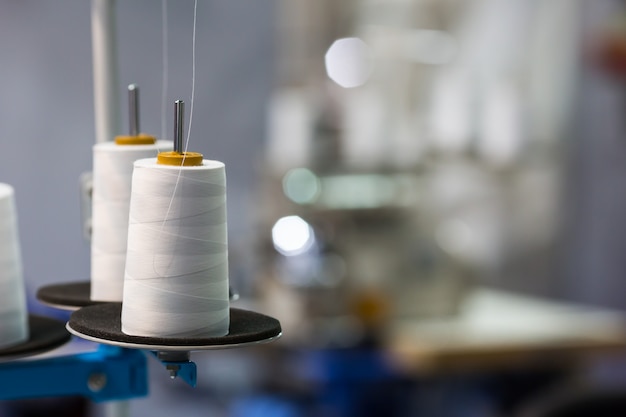 Photo spools of white threads on sewing machine, closeup