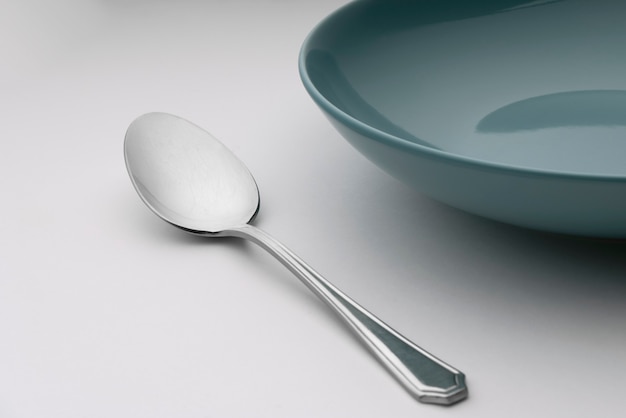 Photo a spoon next to a blue plate on a table