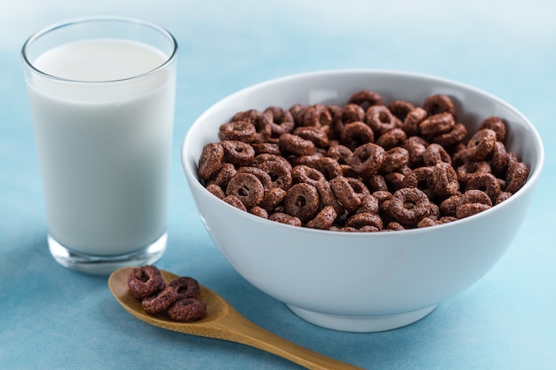 Photo spoon and bowl with chocolate rings and a glass of milk for dry, cereals breakfast