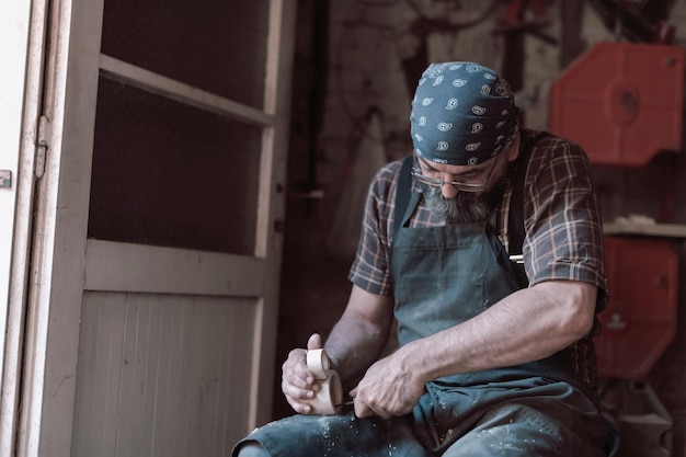 Cucchiaio maestro artigiano nella sua bottega con prodotti in legno fatti a mano e attrezzi da lavoro. foto di alta qualità