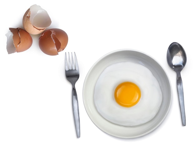 Ложка вилка жареное яйцо на тарелке на белом фоне