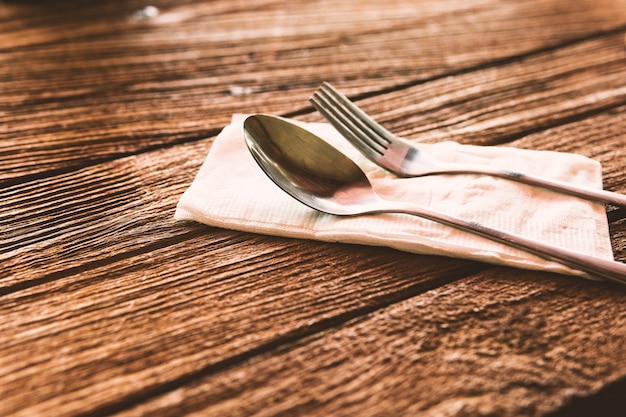 Spoon and fork put on paper with wooden floor.