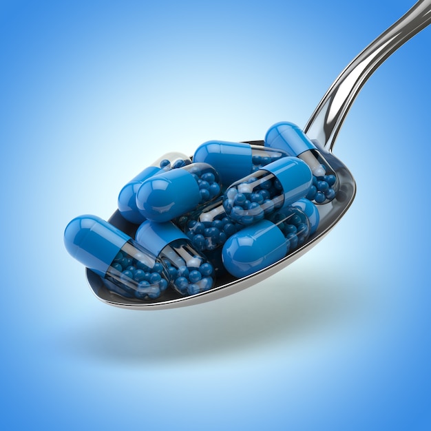 Spoon full of capsules and pills on the blue background